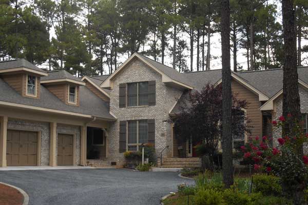Vinyl siding and stone house with custom shingle roofing laid down by Creed & Garner Roofing Company Inc. in Aberdeen, NC.